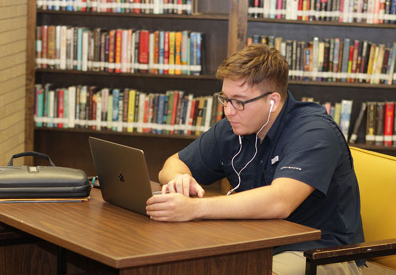 male student studying on a laptop at the library